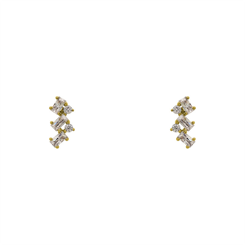 A pair of crystal cluster studs with 2 round cut and 3 baguette cut crystals set in 14 kt yellow gold vermeil on a white background.