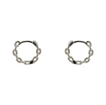 A pair of hinged huggie hoops with chain pattern cast in sterling silver. Displayed side facing on a marble background.