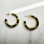 3/4 organic style hoop earrings with posts made of 14 kt yellow gold vermeil on an ivory colored tile.