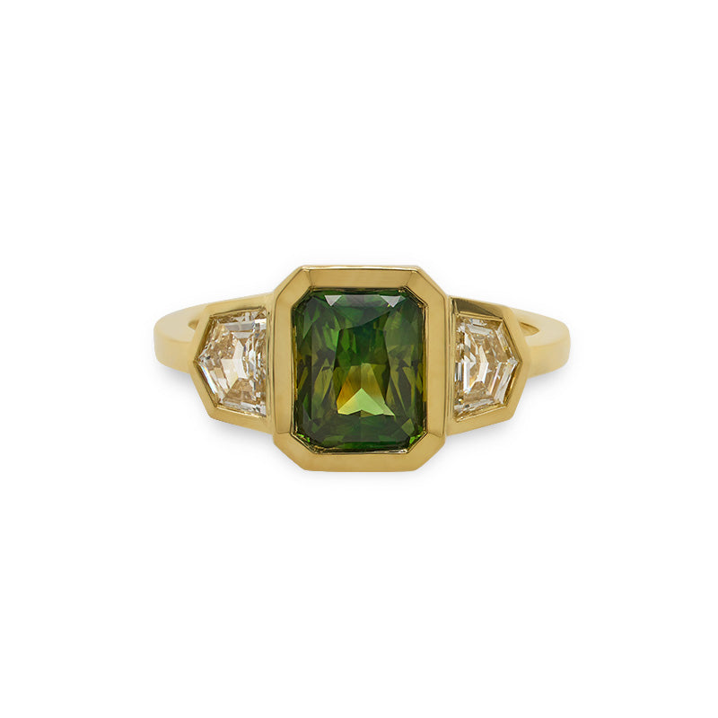 Front view of an emerald cut, green sapphire and Cadillac cut diamond ring cast in 18 kt yellow gold.