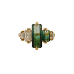 Front facing view of an 18 kt yellow gold ring with a large, elongated emerald cut bi-color green tourmaline in the center, set between another bi-color green emerald cut tourmaline and 3 emerald cut diamonds.