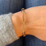 Front view on wrist of a paperclip style bracelet with a thinner gauge link cast in solid 14 kt yellow gold.