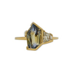 Front view of a light blue with yellow bicolor sapphire, cut in an irregular geometric shape with a trapezoid cut white diamond set alongside. Cast in 18 kt yellow gold.