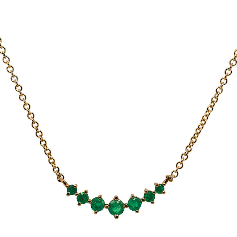 Front view of a large sized 7 stone graduated emerald pendant necklace cast in 14 kt yellow gold.  