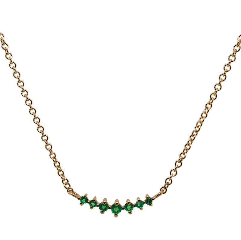 Front view of a small sized 7 stone graduated emerald pendant necklace cast in 14 kt yellow gold.