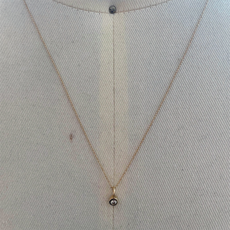 View of bezel set diamond charm on fine gold chain set in 14k yellow gold.