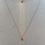 View of bezel set diamond charm on fine gold chain set in 14k yellow gold.