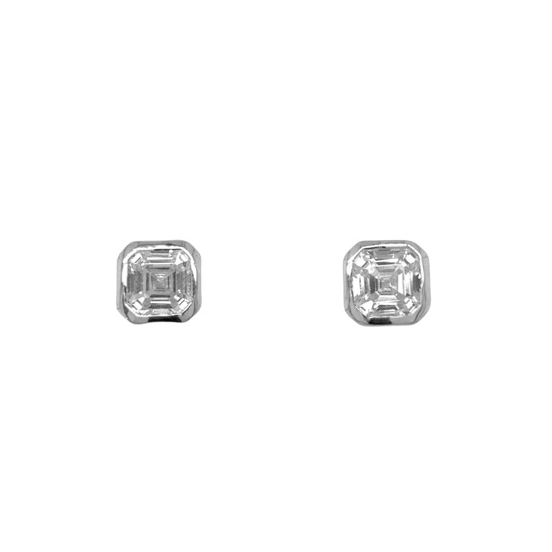 A pair of asscher cut bezel set studs in sterling silver shown on a white background.