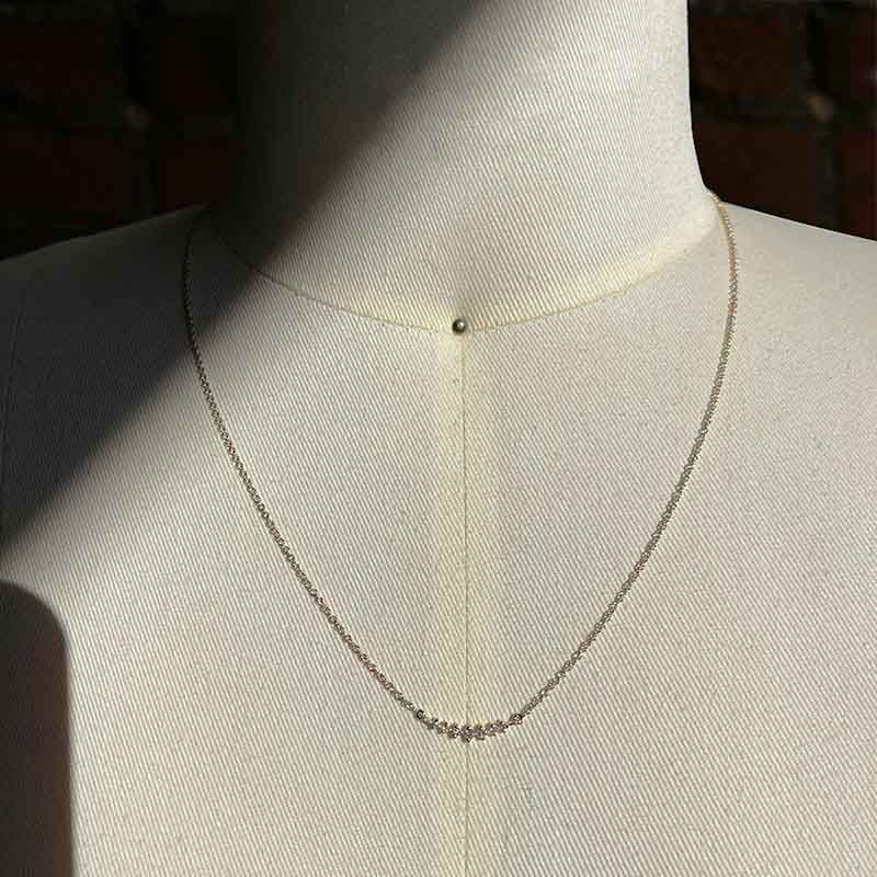 Graduated diamond necklace with 7 round cut diamonds set in 14 kt yellow gold, and on a body form for scale.