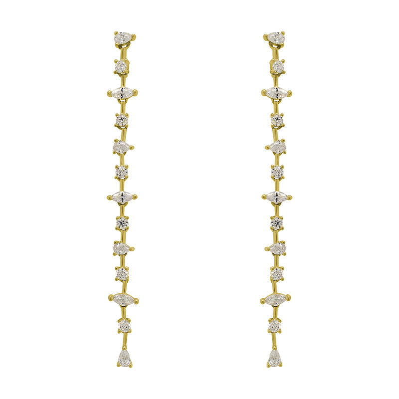 A pair of 14 kt yellow gold vermeil drop earrings with round, pear and marquise cut crystals in front of an ivory colored tile background.