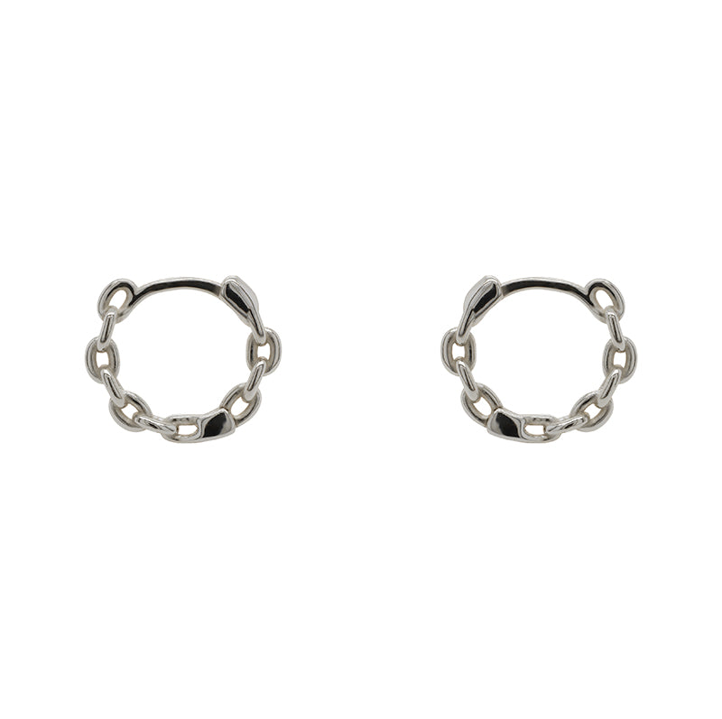 A pair of hinged huggie hoops with chain pattern cast in sterling silver. Displayed side facing on a marble background.