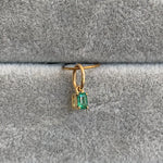 closeup of .16ct emerald charm suspended from oversized bail set in 14k yellow gold.