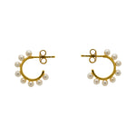 These 3/4 wire hoop earrings are made of 925 sterling silver with 14kt yellow gold vermeil. Each hoop is adorned with 8 pearls and measure at 17.25 mm. Displayed side facing on a marble background.