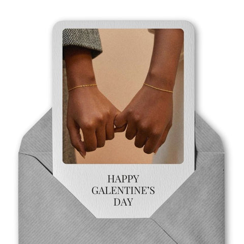 Image of photo invitation with 2 friends interlocking pinkies with dainty gold bracelets on each.