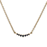Front view of a graduated, blue sapphire necklace with 7 round cut sapphires set in 14 kt yellow gold.
