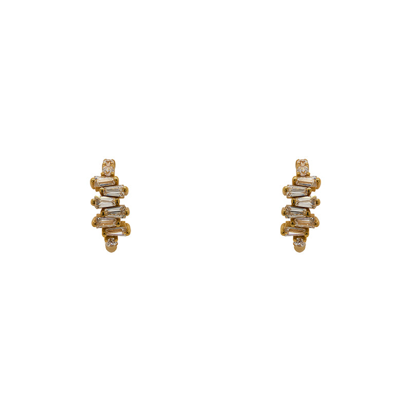 
                  
                    Load image into Gallery viewer, A pair of huggie style earrings made of 14kt yellow gold vermeil with tapered baguette crystals. Displayed forward facing on a white background.
                  
                