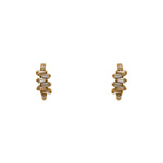 A pair of huggie style earrings made of 14kt yellow gold vermeil with tapered baguette crystals. Displayed forward facing on a white background.