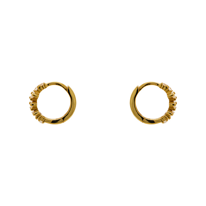 A pair of huggie style earrings made of 14kt yellow gold vermeil with tapered baguette crystals. Displayed side facing on a white background.