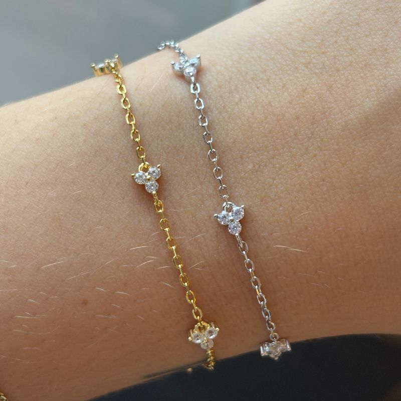 A styled photo of a sterling and yellow gold bracelet on a model's wrist.