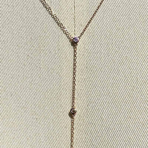 
                  
                    Load image into Gallery viewer, Close up of a lariat style necklace with 9 petite round cut, bezel set diamonds cast in 14 kt rose gold settings on a body form for perspective.
                  
                