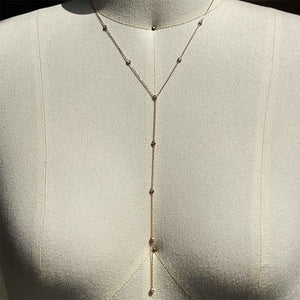 
                  
                    Load image into Gallery viewer, Lariat style necklace with 9 petite round cut, bezel set diamonds cast in 14 kt rose gold settings on a body form for perspective.
                  
                