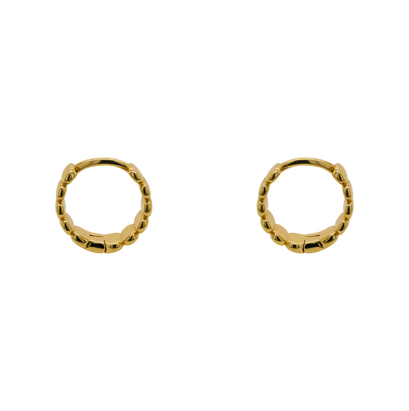 Pair of hinged huggie earrings with a flat organic texture. 4.6mm wide and made of sterling silver with a 14kt yellow gold plating. Displayed side facing on a white background.