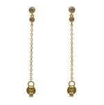 A pair of milgrain, bezel set round crystal studs with a smaller hanging bezel set crystal and chain connected to the earring back, and made of 14 kt yellow gold vermeil.