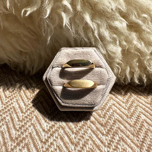 
                  
                    Load image into Gallery viewer, One 14 kt gold high polish and one matte finish signet ring in a ring holder with a woolen pillow and chevron style pattern blanket in the background.
                  
                