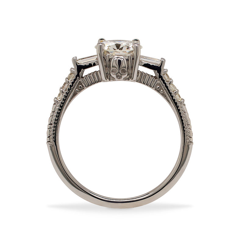 
                  
                    Load image into Gallery viewer, Side view of a round cut diamond engagement ring made of 14 kt white gold with baguette and round cut diamonds going down the shank and a skull engraved on the side.
                  
                