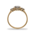 Side view of a salt and pepper diamond ring with one large, round center stone between 2 smaller round stones cast in 14 kt yellow gold by King + Curated.