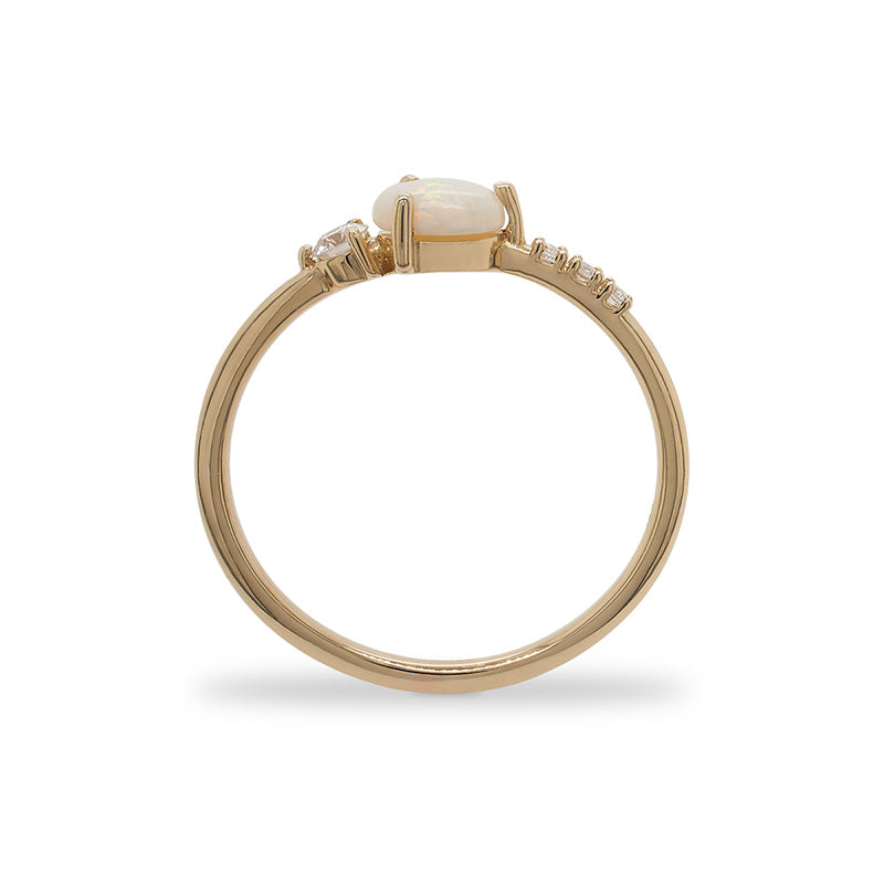 Side view of an asymmetrial ring with a center opal flanked by 3 small round diamonds and 1 medium size round diamond cast in 14 kt yellow gold by King + Curated.