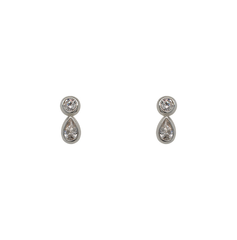 A pair 925 sterling silver stud earrings with one bezel set round crystal and one larger bezel set pear cut crystal on a white background.