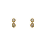 A pair of 14 kt yellow gold vermeil stud earrings with one bezel set round crystal and one larger bezel set pear cut crystal on a white background.