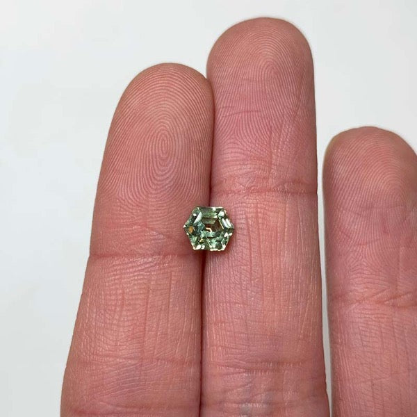 View of 1.13 green-blue hexagon cut sapphire on ladies hand for scale.