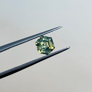 
                  
                    Load image into Gallery viewer, View of 1.13 green-blue hexagon cut sapphire in tweezers.
                  
                