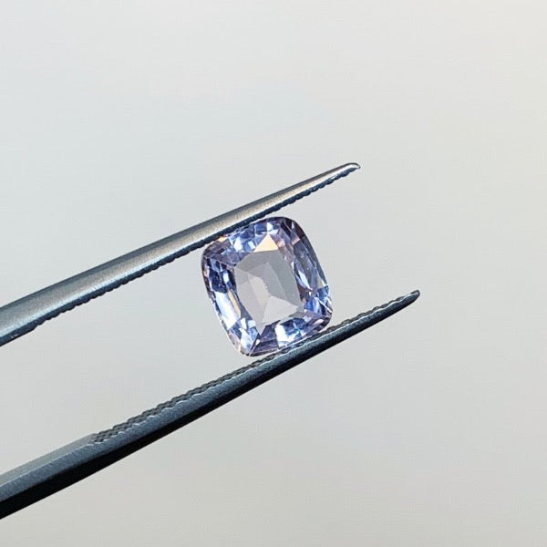View of a 1.30 ct. cushion cut pale lilac sapphire in tweezers.