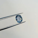 View of a 1.68 ct. blue oval sapphire in tweezers.