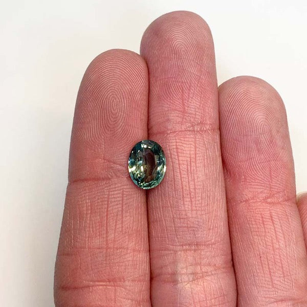 View of an oval 2.06 ct. blue-green sapphire on ladies hand for scale.