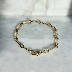 
                  
                    Load image into Gallery viewer, Overhead view of a paperclip and single ring bracelet made of solid 14 kt yellow gold with a lobster claw style closure.
                  
                