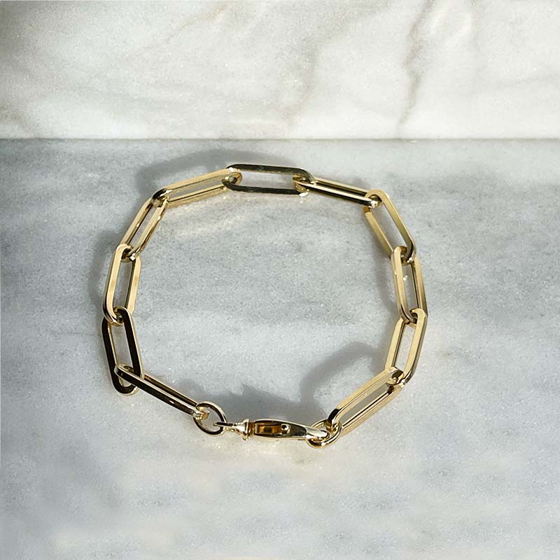 Overhead view of a solid 14kt yellow gold  7" thick gauge paperclip style bracelet with a lobster clasp style closure.