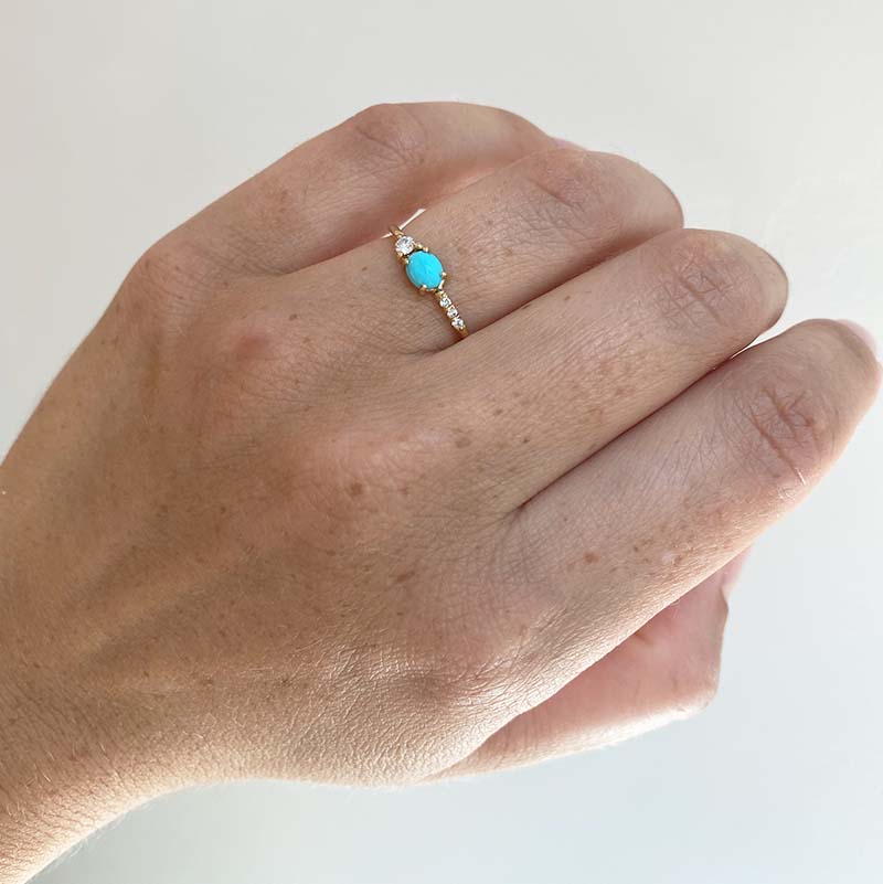 
                  
                    Load image into Gallery viewer, Front view on left ring finger of an asymmetrical cabochon turquoise ring with 3 small diamonds and 1 medium size diamond and cast in 14 kt yellow gold.
                  
                