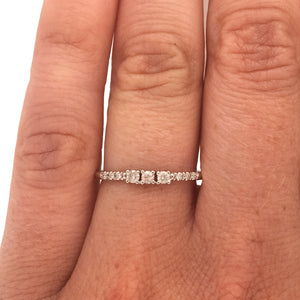 
                  
                    Load image into Gallery viewer, A diamond ring with 3 center round cut diamonds flanked by 6 round cut pavé set diamonds cast in 14 kt white gold on wearer&amp;#39;s left ring finger for scale.
                  
                