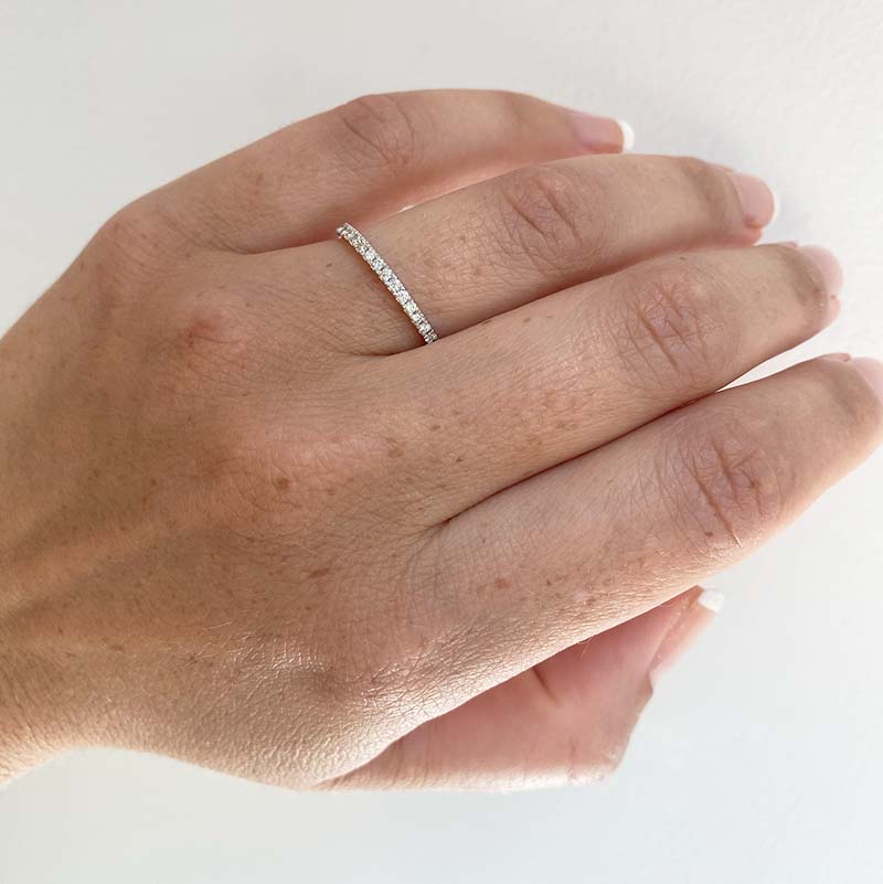 Round cut diamond eternity band with a tcw of 0.47, cast in 14 kt white gold, and worn on the left ring finger for scale.