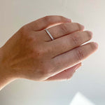 Front view on left ring finger of a half eternity band with a tcw of 0.47 round cut diamonds cast in 14 kt white gold.