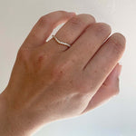 Front view on ladies left ring finger of a shadow band with 27 one and a half mm round diamonds set in 14 kt Yellow gold.