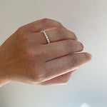 Front view on left ring finger of a half eternity band with a tcw of 0.53 round cut diamonds cast in 14 kt white gold.
