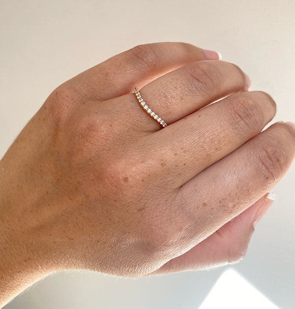 View on left ring finger of diamond Kari shadow band with 21 round cut diamonds for a tcw of 0.32, and cast in 14kt rose gold.