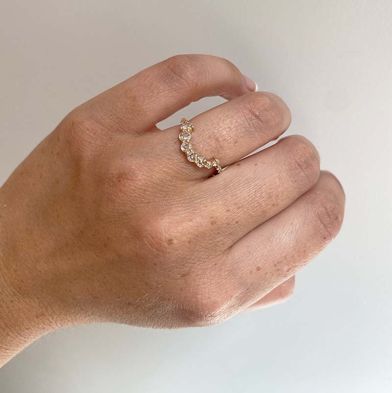 Asymmetrical, rose cut diamond shadow band with 7 rose cut diamonds and 10 round cut diamonds set in 14 kt yellow gold on left ring finger for scale.