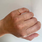 Front view on left pinky finger of a V shaped ring with 10 round cut diamonds cast in 14 kt yellow gold by King + Curated.