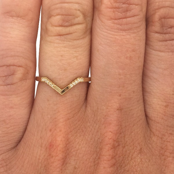 V shaped ring with 10 round cut diamonds cast in 14 kt yellow gold by King + Curated on left ring finger for scale.